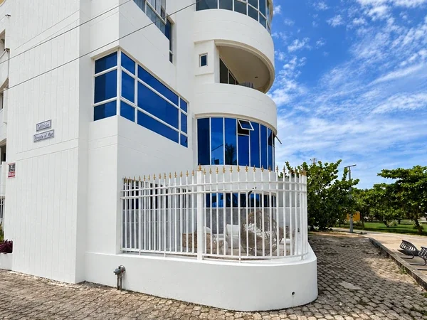 Fachada blanca y ventanas azules del Edificio Frente al Mar, con nuestro showroom detrás de la reja del primer piso